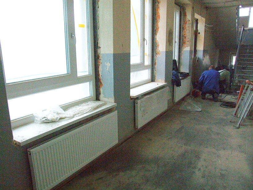 Lang gestreckte, flache Heizkörper vor jedem Fenster eines Schulraumes