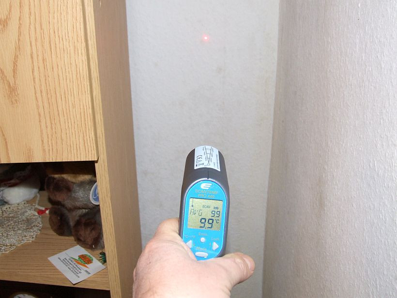 Im Bild wird mit einem Infarotthermometer die Oberflächentemperatur in einer Außenwandecke gemessen