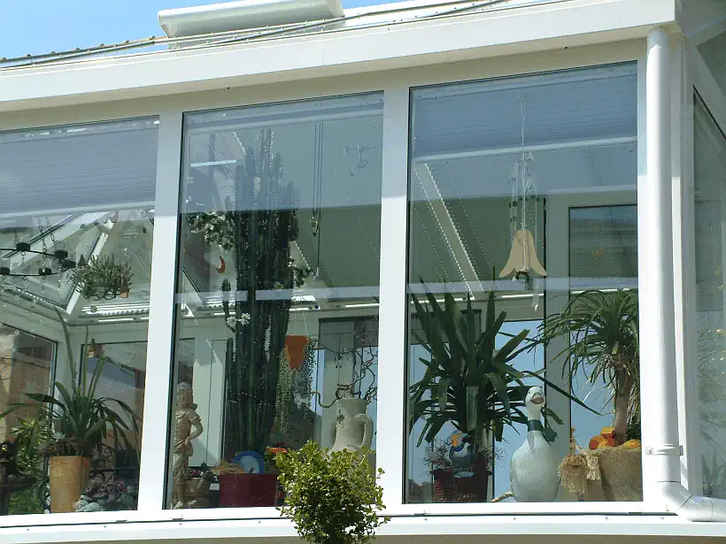Wohn-Wintergarten mit innenliegender Verschattung und mediterranem Bewuchs